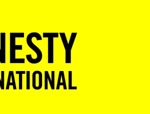 Logo von Amnesty International mit schwarzem Text auf gelbem Hintergrund und einer mit Stacheldraht umwickelten Kerze auf der rechten Seite.