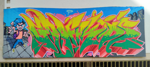 Buntes Graffiti-Wandbild mit einer Cartoon-Figur mit Mütze und Sonnenbrille auf der linken Seite, fetten gelben und grünen stilisierten Buchstaben in der Mitte und städtischen Gebäuden im Hintergrund vor einem blauen Himmel.